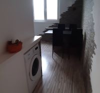 Étkező sarok fa mintás padlóval, mosógéppel és érdekes fallal egy kétszobás lakásban.