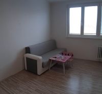 Nappali egy kétszobás lakásban kanapéval és asztallal, fa dekorációjú padlóval.