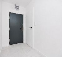 Előszoba szürke ajtókkal és fehér falakkal egy háromszobás lakásban.