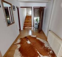 Családi ház belső tere fa dekorációjú padlóval és korláttal ellátott lépcsővel.