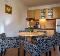 Konyhasarok étkezőasztallal és székekkel a nyaraló apartmanban, fa dekorációjú padlóval.