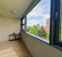 Üvegezett loggia egy 3 szobás lakásban, kilátással a zöldövezetre és a városi panorámára.