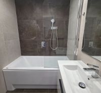 Fürdőszoba egy háromszobás lakásban káddal, zuhanyfallal és modern mosdóval.