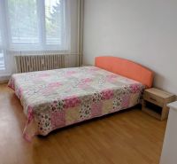 Hálószoba ággyal és patchwork ágytakaróval egy kétszobás lakásban, fa dekor padlóval.