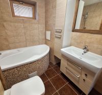 Fürdőszoba sarokkáddal, mosdóval és WC-vel egy kétszobás lakásban.