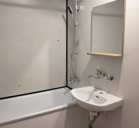 Fürdőszoba egy háromszobás lakásban, káddal és mosdóval ellátott zuhanyfejjel.