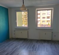 3 szobás lakás szobája fa mintázatú padlóval és kék fallal.