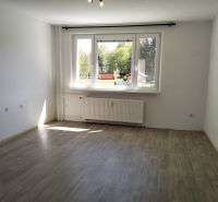 Világos, üres belső tér nagy ablakkal és fa dekorációjú padlóval egy háromszobás lakásban.