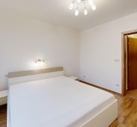 Világos hálószoba ággyal, fa dekoros padlóval és minimalista világítással egy háromszobás lakásban.