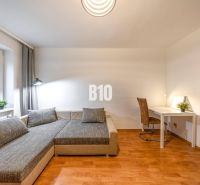 Nappali egy kétszobás lakásban kanapéval, asztallal és fa dekorációjú padlóval.