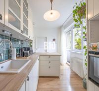 Konyha egy kétszobás lakásban fa dekor padlóval és fehér szekrényekkel.