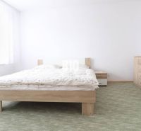 Hálószoba egy háromszobás lakásban, franciaággyal, fehér bútorokkal és szőnyeggel.