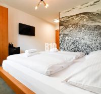 Rekreációs apartman belső tere kényelmes ággyal, dekoratív fallal és televízióval.