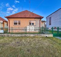 Családi ház Sľažanyban előkerttel és ferde tetővel a szomszédos épületek között.