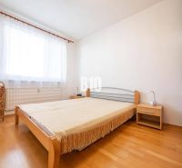 Hálószoba egy kétszobás lakásban, ággyal és fa dekorációjú padlóval.