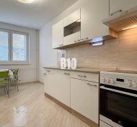 Világos konyha a Nyaraló apartmanban tűzhellyel és asztallal zöld székekkel.