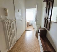 Háromszobás lakás folyosója fa dekor padlóval és bejárattal a konyhába.