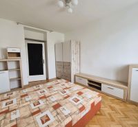 Hálószoba ággyal, tárolóbútorral és fa dekoros padlóval egy háromszobás lakásban.