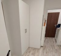 Hangulatos garzon fehér bútorokkal és fa mintázatú padlóval.