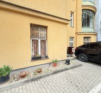 Parkolás az épület előtt a Leškova utcában, Pozsonyban, virágtartókkal és parkoló autóval.