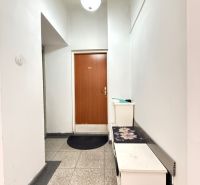 Folyosó fehér falakkal és barna ajtókkal egy kétszobás lakásban.