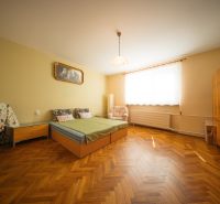 Hálószoba családi házban ággyal, szekrénnyel és fa mintázatú padlóval.