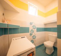 Fürdőszoba családi házban WC-vel és mosógéppel, virágmintás csempékkel.