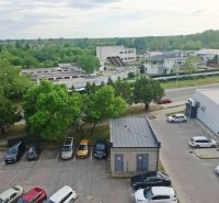Parkoló autókkal, zöldterülettel és épületekkel Érsekújváron, a Nábrežná utcában.
