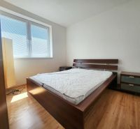 Hálószoba napfénnyel, ággyal, éjjeliszekrénnyel és fa dekorációjú padlóval.
