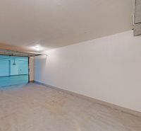 Nyitott ajtajú garázsok, fehér falakkal és padlóval Pozsonyban - Petržalkán.