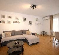 Kényelmes nappali tér egy üdülő apartmanban fa dekorációjú padlóval és étkezőasztallal.