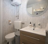 Fürdőszoba a nyaraló apartmanban mosdóval, tükörrel és WC-vel.
