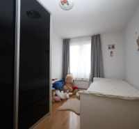 Gyerekszoba a Nyaraló apartmanban ággyal, szekrénnyel és plüss játékokkal a padlón, fa dekorációval.
