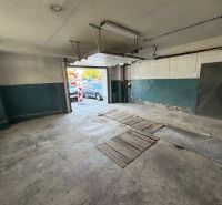 A nyitott ajtajú garázs, beton padló. Autó nélkül.