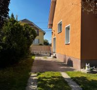 Családi ház Csallóközben narancssárga homlokzattal, gyepesített udvarral és szilárd burkolatú bejárati úttal.