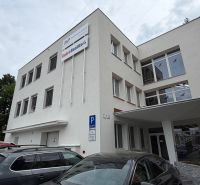 Irodaház a Prievidza Dlhá utcáján parkoló autókkal.