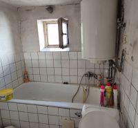 Fürdőszoba családi házban csempékkel, káddal és bojlerrel.