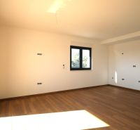 Tágas szoba nagy ablakkal és fa dekorációjú padlóval az üdülő apartmanban.
