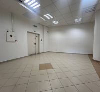 Üres üzlethelyiség csempézett padlóval, fehér falakkal, mennyezeti világítással.