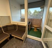 Világos loggia egy 4 szobás lakásban kilátással és fa bútorokkal.