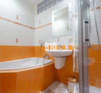 Fürdőszoba egy kétszobás lakásban, domináns narancssárga csempékkel és káddal.