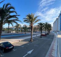 Pálmafák és az út mentén parkoló autók apartmanok mellett La Manga del Mar Menorban, Spanyolország.