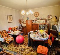 Egy háromszobás lakás szobája, amely tele van vintage bútorokkal és dekorációkkal, fa dekoros padlóval.