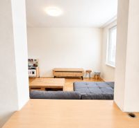Nappali egy kétszobás lakásban világos bútorokkal és fa dekorációjú padlóval.