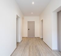 Folyosó egy családi házban, fa mintázatú padlóval és fehér falakkal.