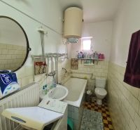 Fürdőszoba tükörrel, mosdóval, káddal és mosógéppel egy családi házban.