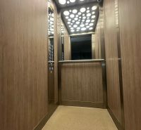 A lift belső tere egy kétszobás lakásban, fa dekorációval a falakon.