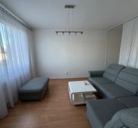 Nappali szürke kanapéval, asztallal és fa dekoros padlóval egy háromszobás lakásban.