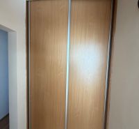 Tolóajtós szekrény és fa dekorációjú padló a háromszobás lakásban.