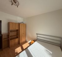Hálószoba egy háromszobás lakásban fehér falakkal és fa dekoros padlóval.